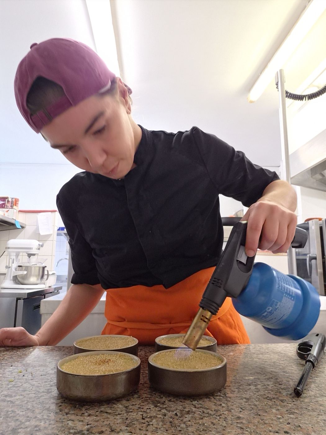 Personne utilisant un chalumeau sur des ramequins en cuisine